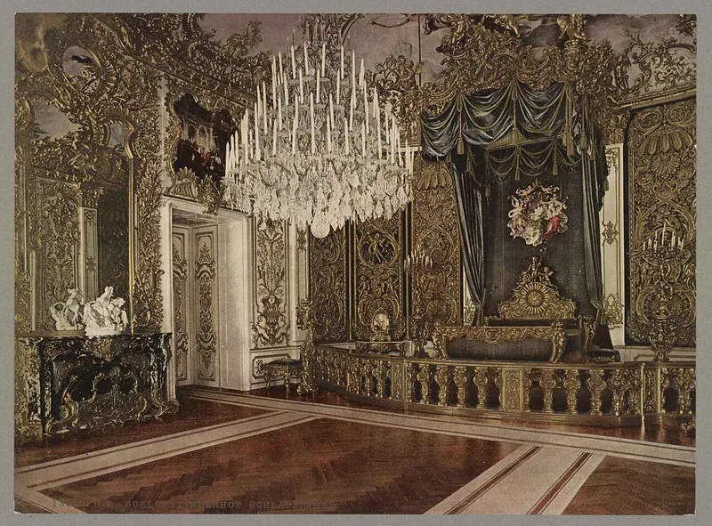 The state bedroom, its bed railed off behind a gilded balustrade beneath a crystal chandelier