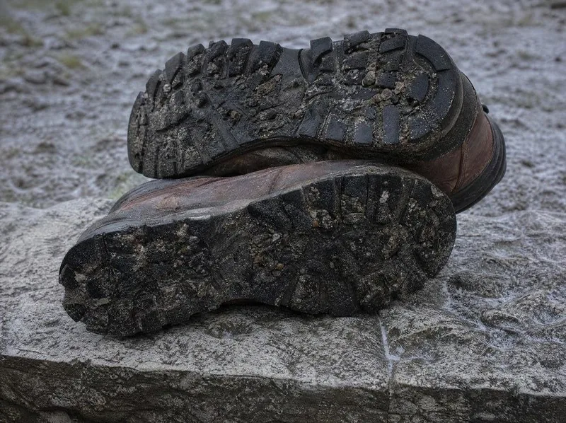 Boot soles on wet gravel, with grit caught in the tread