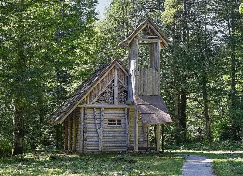 The Hermitage of Gurnemanz, a small steep-roofed timber hut among conifers