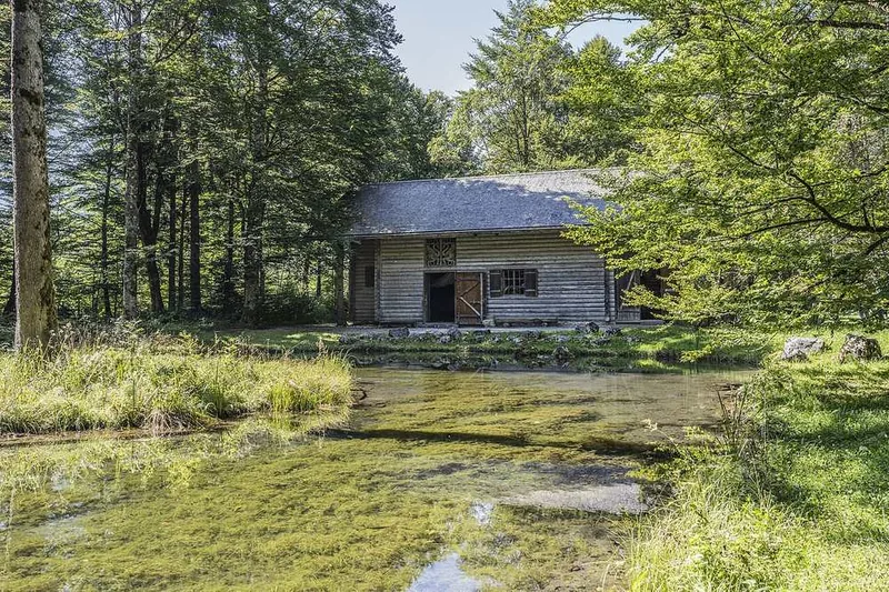 Hunding's Hut, a low timber building with a shingled roof standing alone in wet meadow